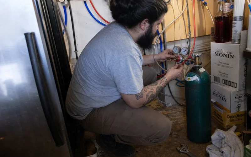 Bartender connecting a CO2 regulator to a beverage dispensing line