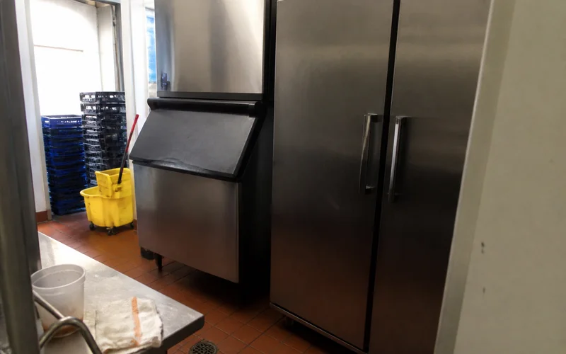 Commercial ice machine and reach-in cooler from major brands in a restaurant