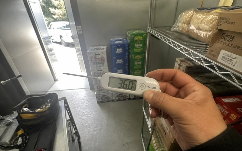 Probe thermometer showing the walk-in cooler back at safe holding temperature after repair