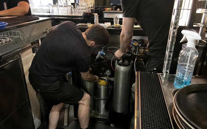 Empty and full CO2 cylinders being swapped behind a busy bar