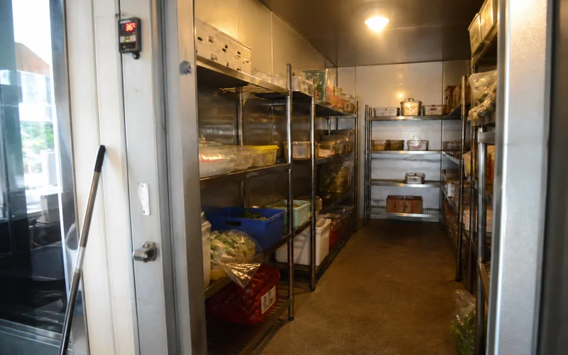 Finished walk-in cooler interior with shelving, lighting, and temperature controller