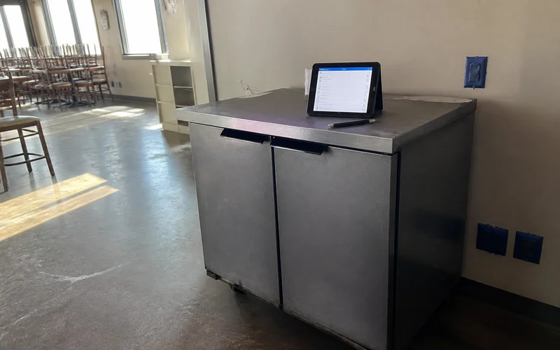 Inspection checklist on a tablet beside an older commercial reach-in cooler