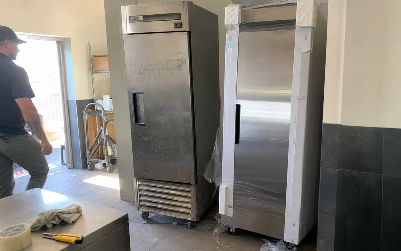 Older worn commercial refrigeration unit beside a newer replacement unit