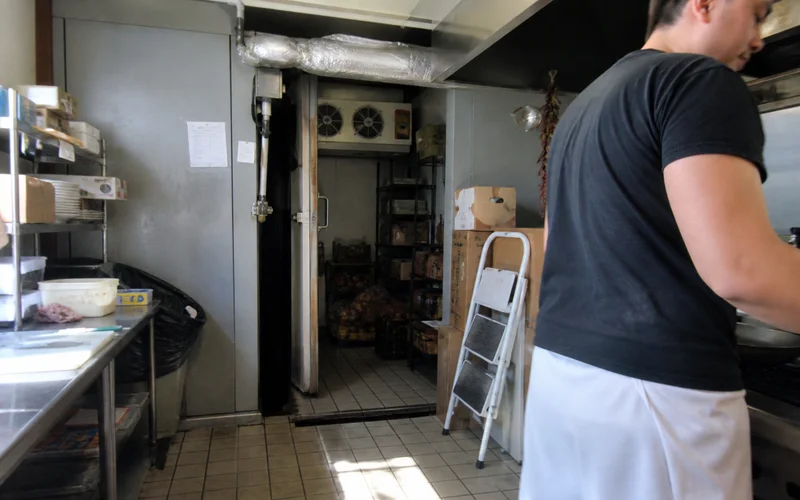 Self-contained refrigeration unit mounted on a walk-in cooler in a compact kitchen