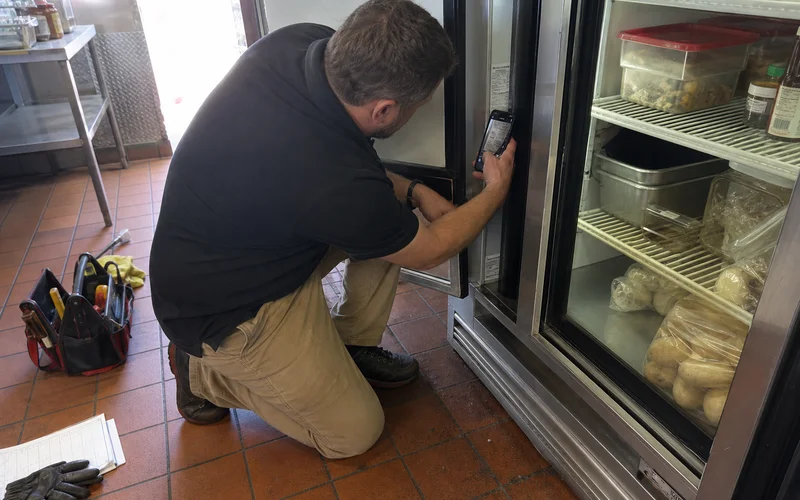 Technician photographing an equipment model and serial plate to verify coverage