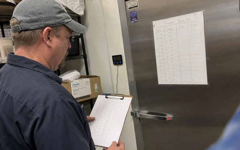 Technician reading a temperature log showing gradual drift on a commercial freezer