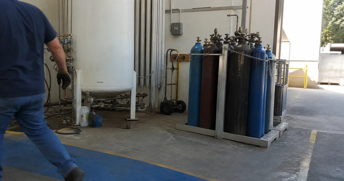 Bulk gas dewar beside a rack of standard high-pressure cylinders
