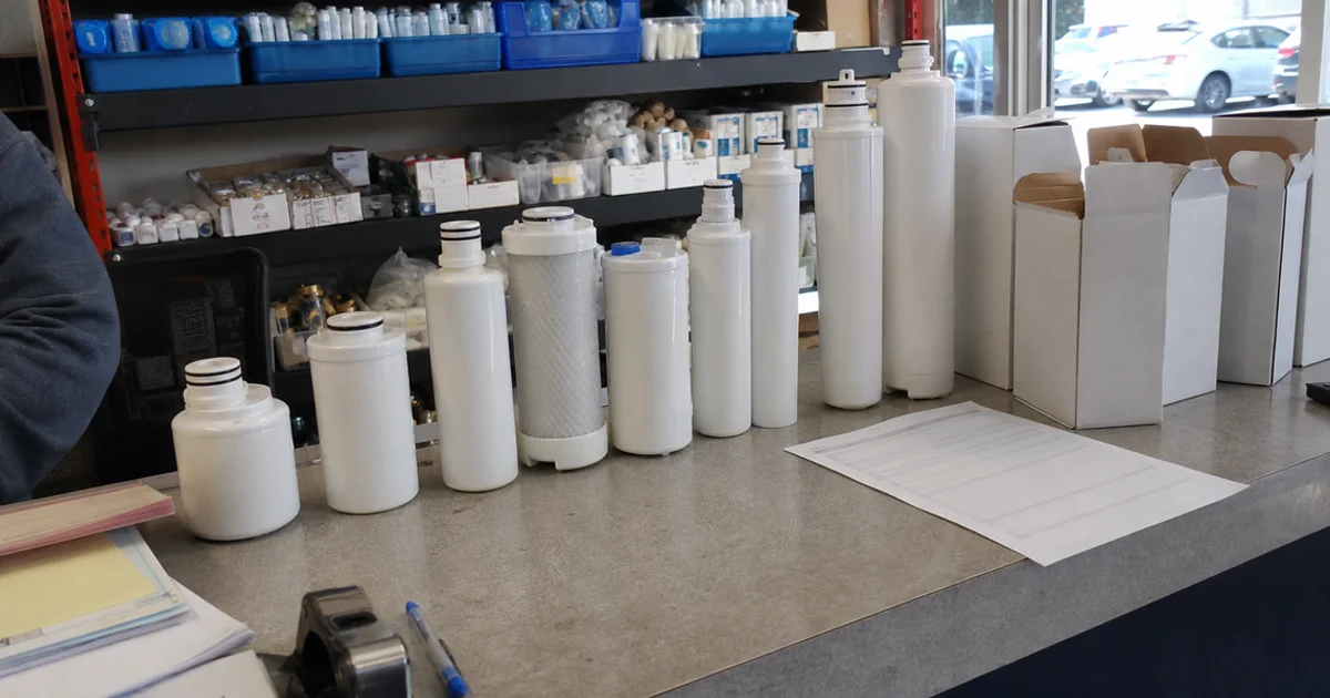 Range of commercial ice machine water filter cartridges on a parts counter