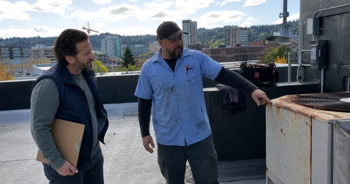 Restaurant owner and technician inspecting an aging commercial condensing unit