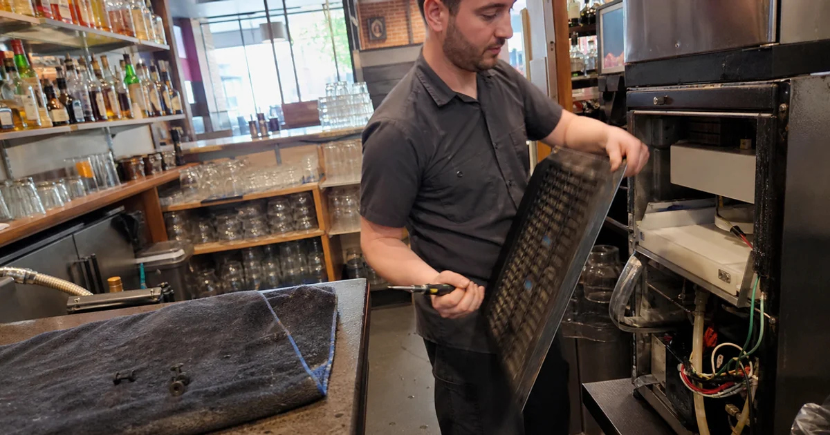 Technician opening a commercial ice machine that has stopped producing ice