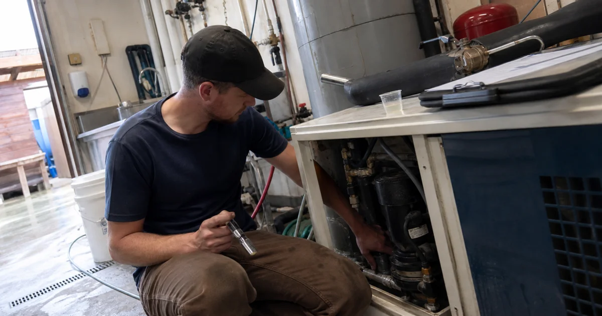 Technician testing glycol concentration and checking the pump on a brewery chiller