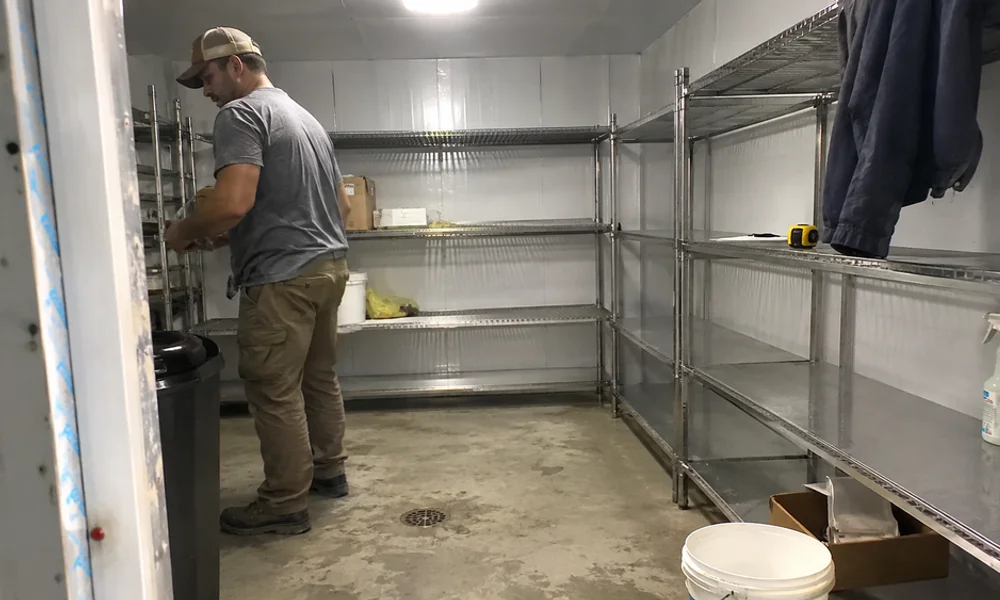 Finished commercial walk-in freezer interior with sealed floor, drainage, and stainless shelving
