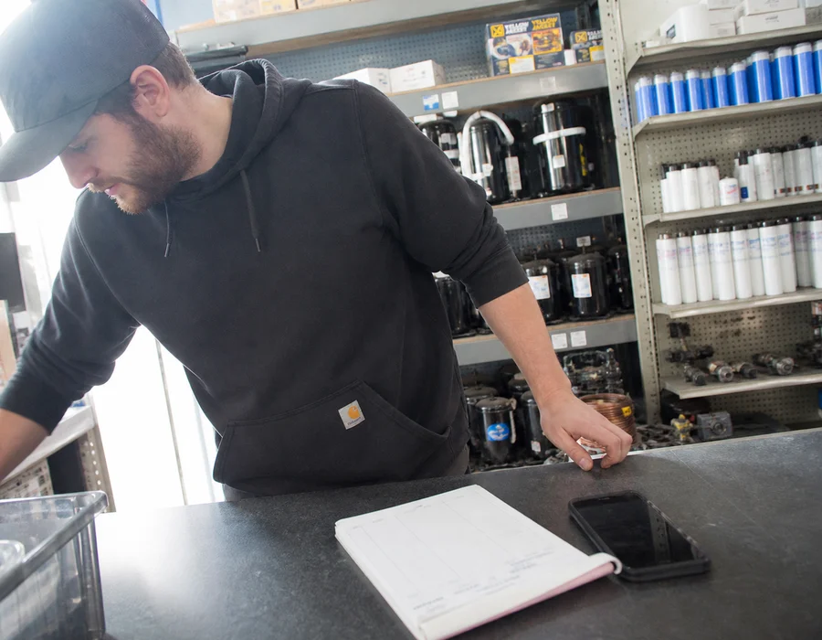 Refrigeration parts counter with compressors, solenoids, gaskets, and water filters on shelving
